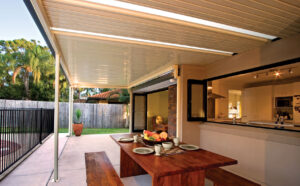 Outdoor dining area with wooden table under pergola.